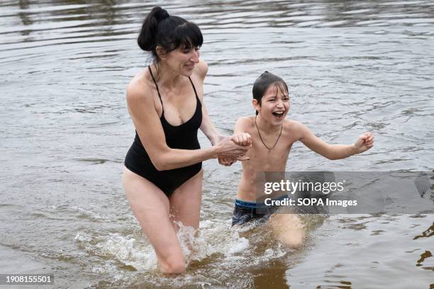 Woman and her son swim in cold waters of Dnipro River on the occasion of the celebration of Epiphany in Kyiv. Ukraine celebrates Epiphany on January...