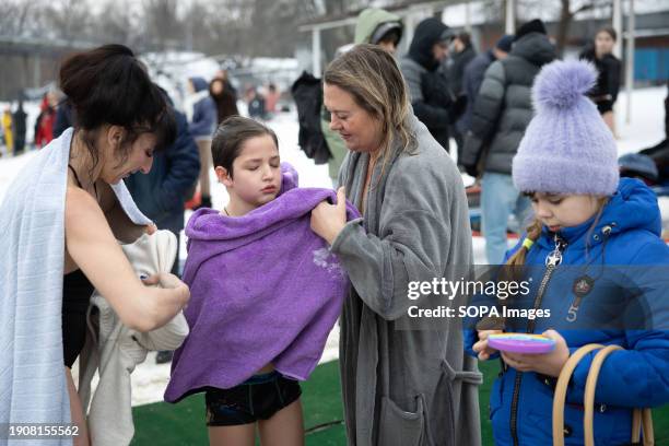 Women help a boy dry himself after swimming in cold waters of Dnipro River on the occasion of the celebration of Epiphany in Kyiv. Ukraine celebrates...