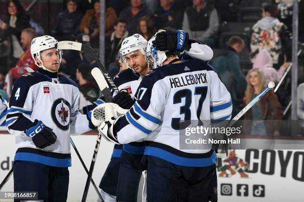 Connor Hellebuyck of the Winnipeg Jets celebrates with teammate Nino Niederreiter after a 6-2 win against the Arizona Coyotes at Mullett Arena on...