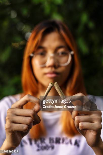 Young woman breaks a cannabis joint in half, embodying the collective effort to curb substance abuse and overcome the challenges of addiction. This...