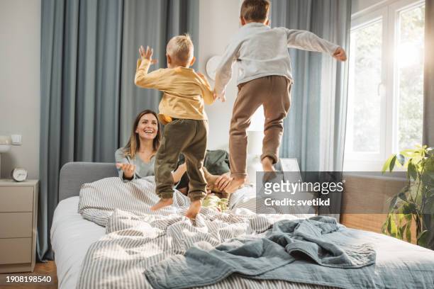 rutina matutina de la familia joven - a boy jumping on a bed fotografías e imágenes de stock