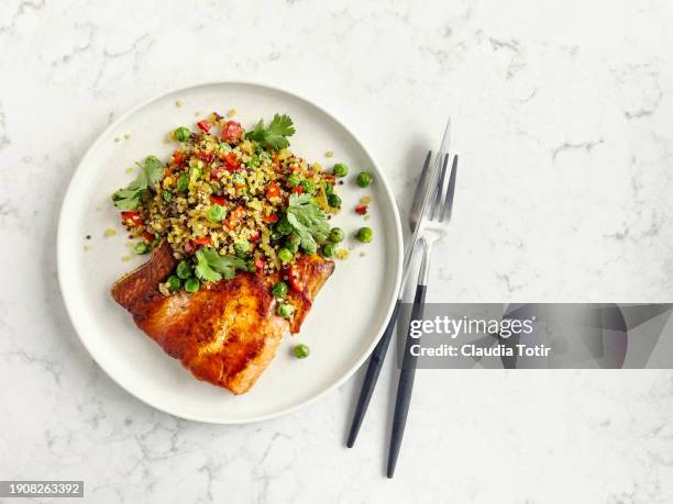 plate of baked salmon and quinoa salad on white, marble background - gegrillter lachs stock-fotos und bilder