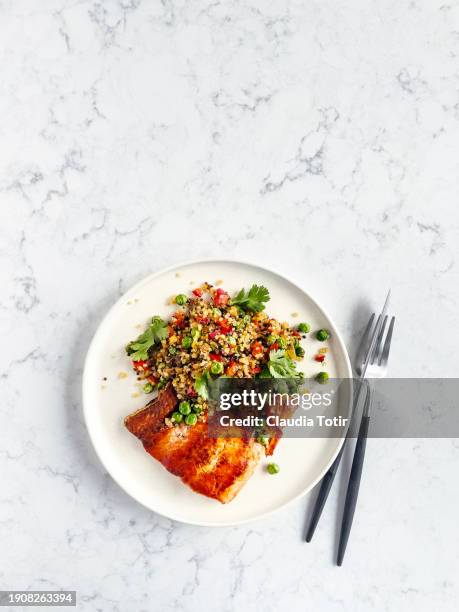 plate of baked salmon and quinoa salad on white, marble background - quinoa stock pictures, royalty-free photos & images