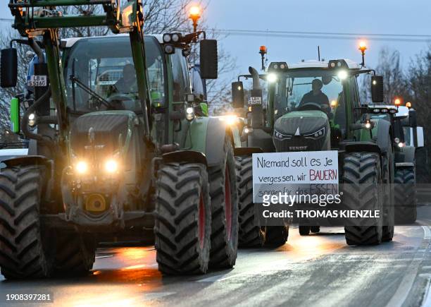 Farmers protest with tractors and a banner reading "Nobody should ever forget, we farmers produce the food" against the federal government's...