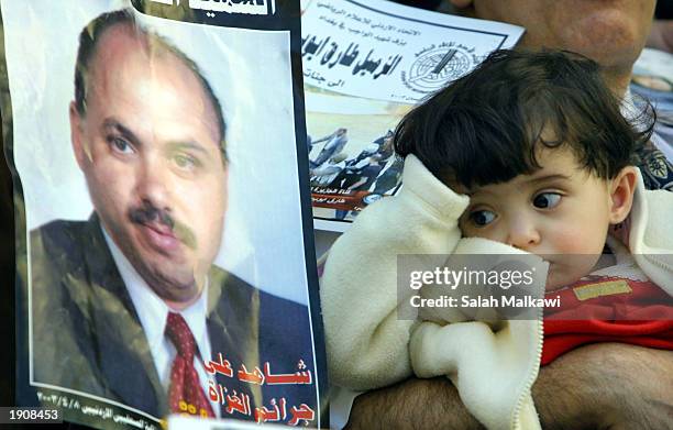 Fatima Ayyoub, the 14-month-old daughter of Jordanian journalist Tareq Naim Ayyoub, looks over at a picture of her father during what friends and...