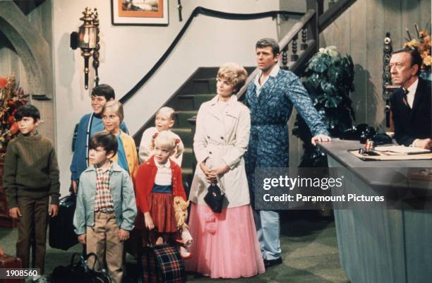 American actors Robert Reed and Florence Henderson stand in a hotel lobby with their television family in a still from the TV series 'The Brady...