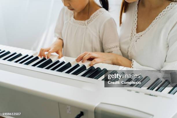 asian mother watching young daughter play keyboard - electric piano fotografías e imágenes de stock