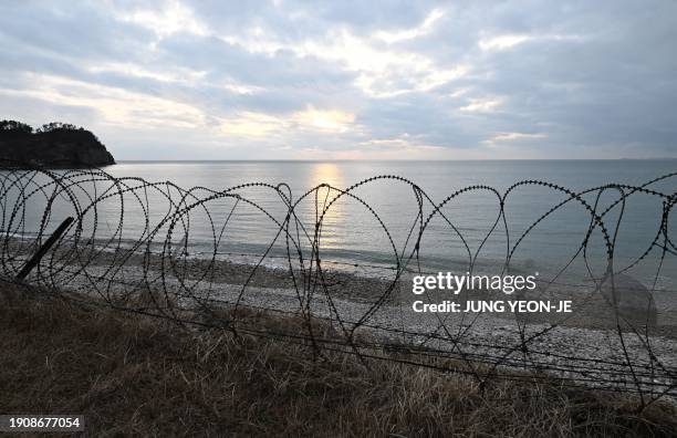 The sunset is seen over a barbed-wire fence on a beach at Yeonpyeong island, near the 'northern limit line' sea boundary with North Korea on January...