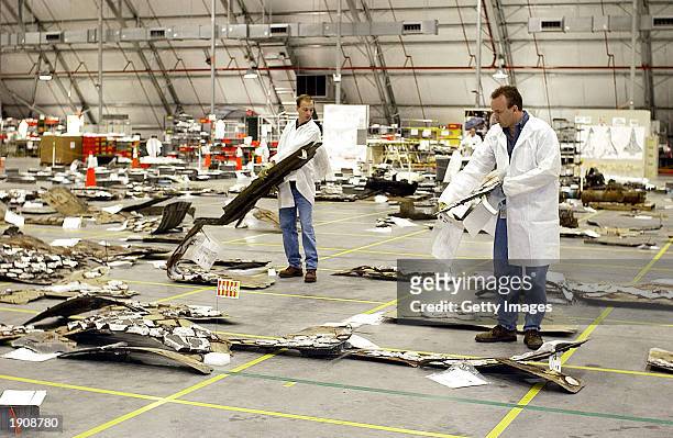 In this NASA handout photo, NASA crash investigators examine debris from the Space Shuttle Columbia April 8, 2003 at Kennedy Space Center, Florida....