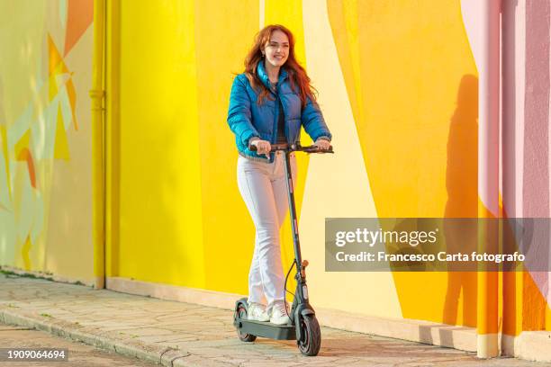 young woman riding electric scooter - trotinete imagens e fotografias de stock