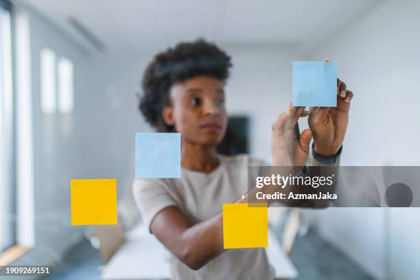 remue-méninges de femme d’affaires avec des notes autocollantes sur verre - flouté photos et images de collection
