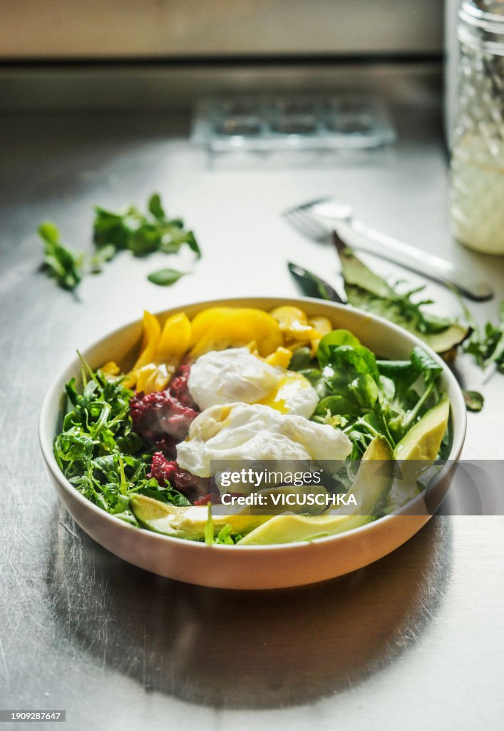 Healthy breakfast bowl with avocado,poached eggs, green salad, yellow and red vegetables
