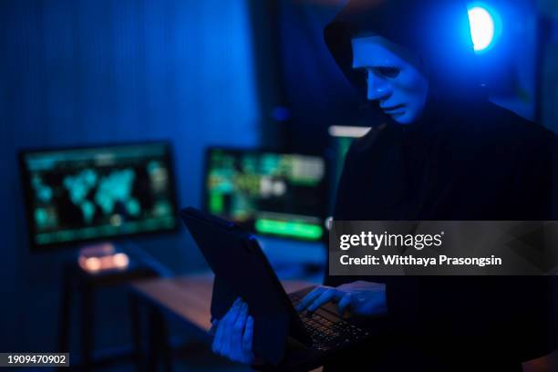 masked hacker in a hoodie standing in corporate data - android malware stockfoto's en -beelden