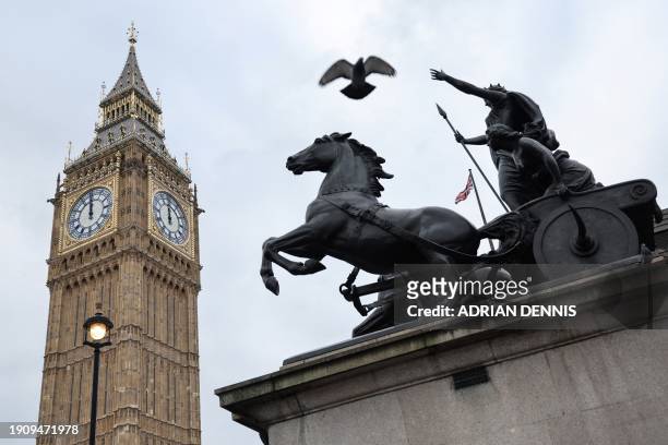 Pigeon flies over Boadicea and Her Daughters statue and the Elizabeth Tower, commonly known by the name of the clock's bell, "Big Ben", at the Palace...