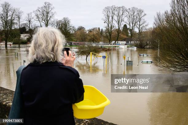 Woman photographs the submerged cars in a car park after heavy rains and sewer system overflows caused the River Thames to break its banks, on...