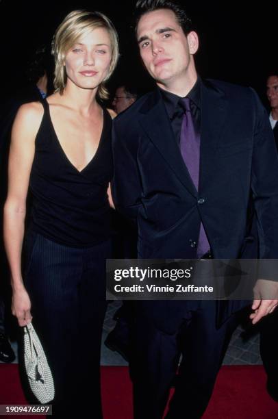 American actress Cameron Diaz, wearing a black v-neck outfit, and American actor Matt Dillon, who wears a black suit over a black shirt with a purple...