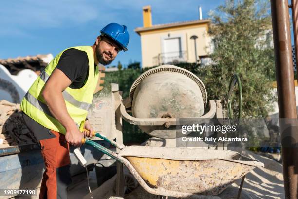 40-year-old construction worker renovating a house in outdoors patio - concrete mixer stockfoto's en -beelden