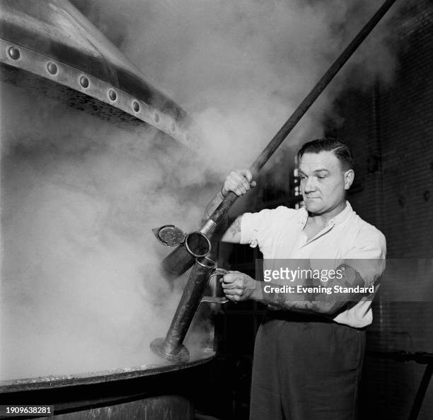 Man taking a beer sample from a brewery vat at the Watney, Combe, Reid & Co Brewery in Pimlico, London, March 14th 1957.
