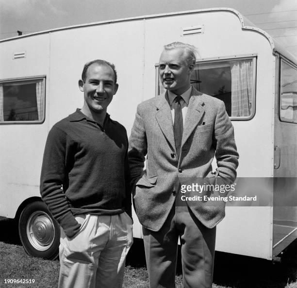 British racing drivers Stirling Moss of Vanwall and Mike Hawthorn of Scuderia Ferrari standing in front of a caravan during the British Grand Prix at...