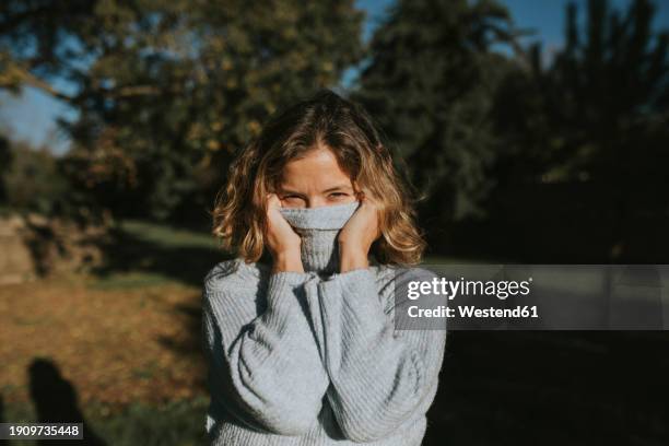 woman covering face with turtleneck sweater - woman hiding in her turtleneck sweater stock pictures, royalty-free photos & images