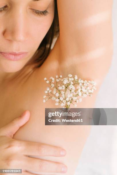 woman with flowers on armpit against white background - achselhöhle stock-fotos und bilder