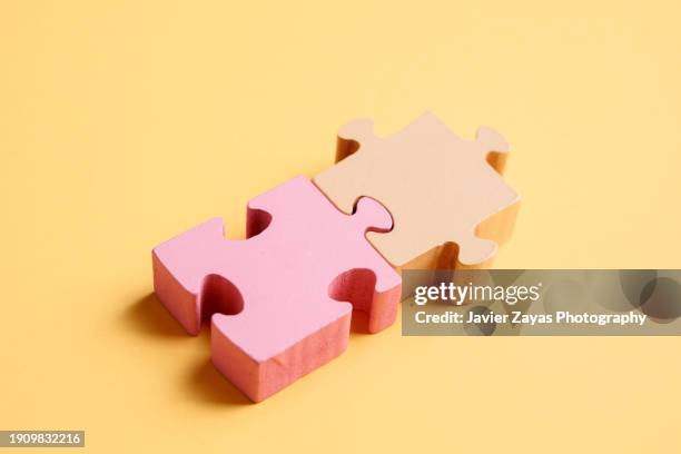 two puzzle pieces on yellow background - déformé photos et images de collection