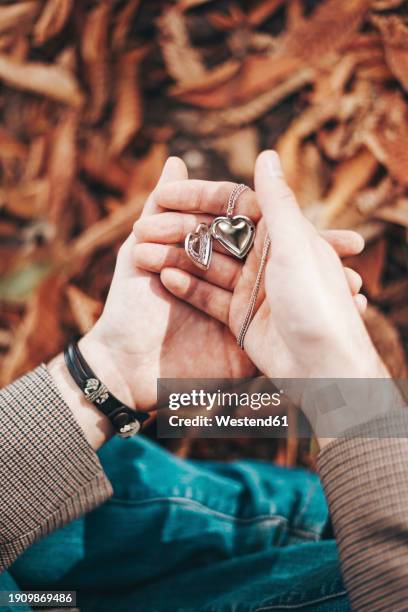 man holding heart shaped necklace in hand - heart locket stock-fotos und bilder