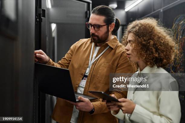 it professionals examining servers with laptop and tablet pc in data center - mainframe stock pictures, royalty-free photos & images