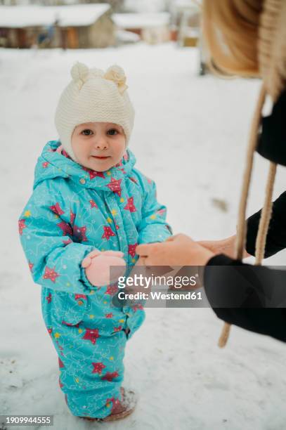 mother putting mittens on daughter's hands in winter - woman hands in mittens stockfoto's en -beelden