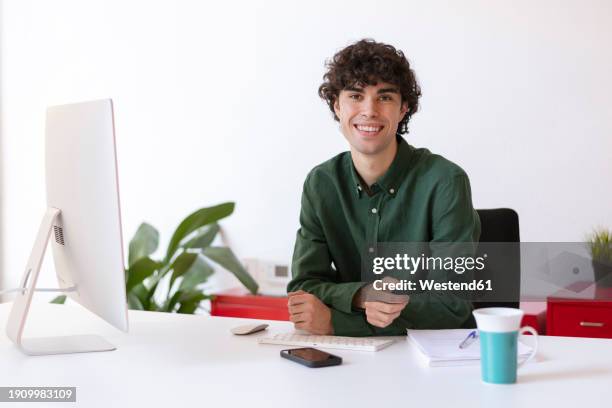 freelancer sitting at desk in home office - grünes hemd stock-fotos und bilder