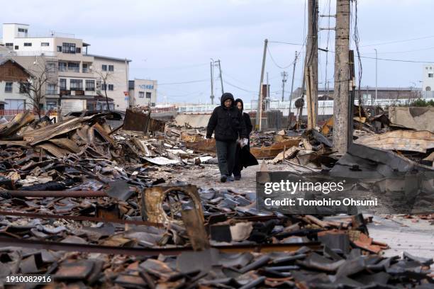 Couple walks through the Asaichi Yokocho, or Wajima Morning Market, area after a fire incident following an earthquake on January 05, 2024 in Wajima,...