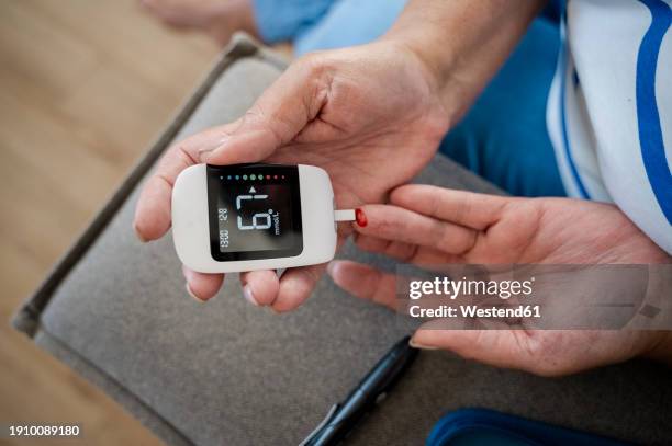 hands of woman using glucometer at home - low section stock pictures, royalty-free photos & images