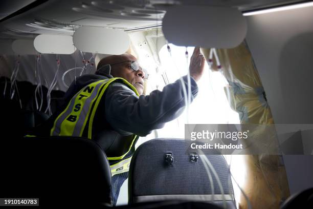 In this National Transportation Safety Board handout, NTSB Investigator-in-Charge John Lovell examines the fuselage plug area of Alaska Airlines...