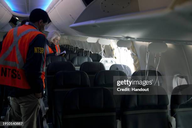 In this National Transportation Safety Board handout, members of the NTSB examine the hole in the fuselage plug area of Alaska Airlines Flight 1282...