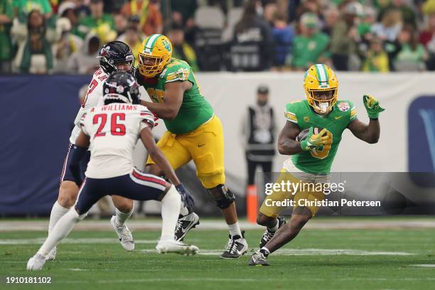 Running back Bucky Irving of the Oregon Ducks rushes the football against the Liberty Flames during the second half of the Fiesta Bowl at State Farm...