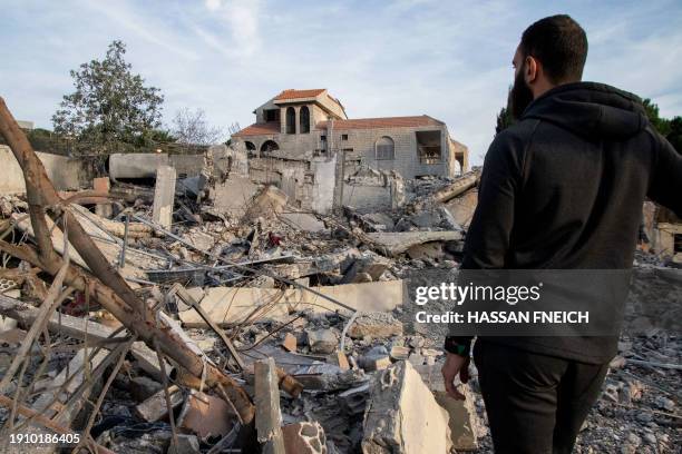 Man checks a destroyed building on January 8, 2024 after an Israeli air raid in the village of Kfar Kila in southern Lebanon, amid ongoing...