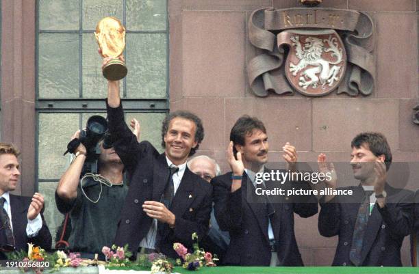 July 1990, Hesse, Frankfurt\Main: The then team manager Franz Beckenbauer holds up the World Cup trophy he won in Italy on the balcony of the Römer,...