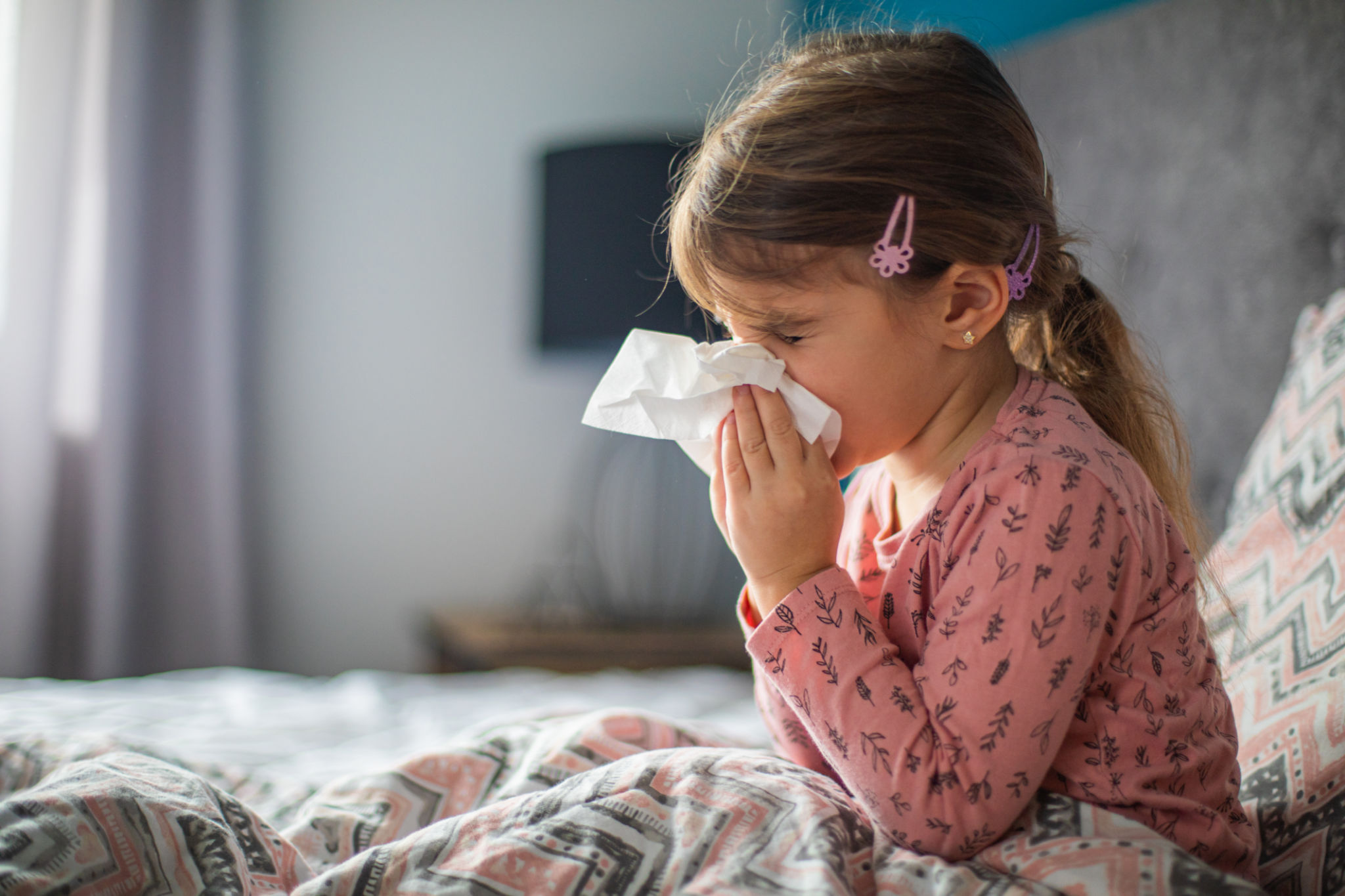 Little girl blowing and wiping her nose with tissue paper in her bedroom Little girl blowing and wiping her nose with tissue paper in her bedroom