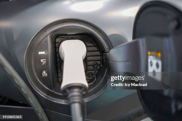 electrical outlet of a car plugged into a charging station - bolardo fotografías e imágenes de stock