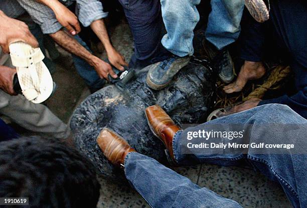 Iraqi civilians stamp on the fallen statue of Saddam Hussein April 9 in the centre of Baghdad.