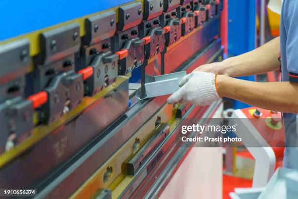 worker loading metal sheet to cnc synchronize hydraulic press brake bending machine. industrial metalworking machinery - hebebühne stock-fotos und bilder