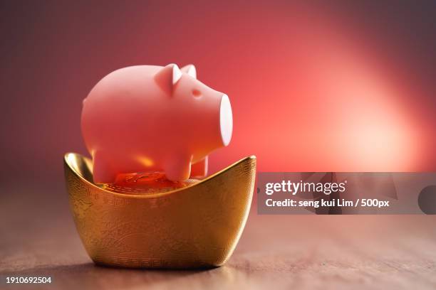 close-up of piggy bank on table against red background - yuanbao stock pictures, royalty-free photos & images