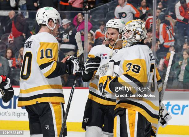 Drew O'Connor, Erik Karlsson, and Alex Nedeljkovic of the Pittsburgh Penguins celebrate after defeating the Philadelphia Flyers 4-1 at the Wells...