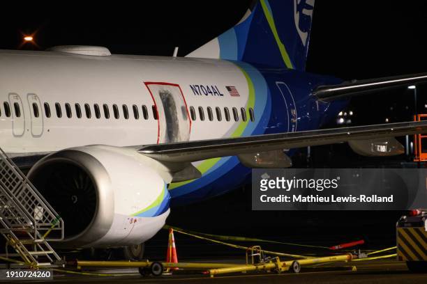 Plastic sheet covers an area of the fuselage of the Alaska Airlines N704AL Boeing 737 MAX 9 aircraft outside a hangar at Portland International...