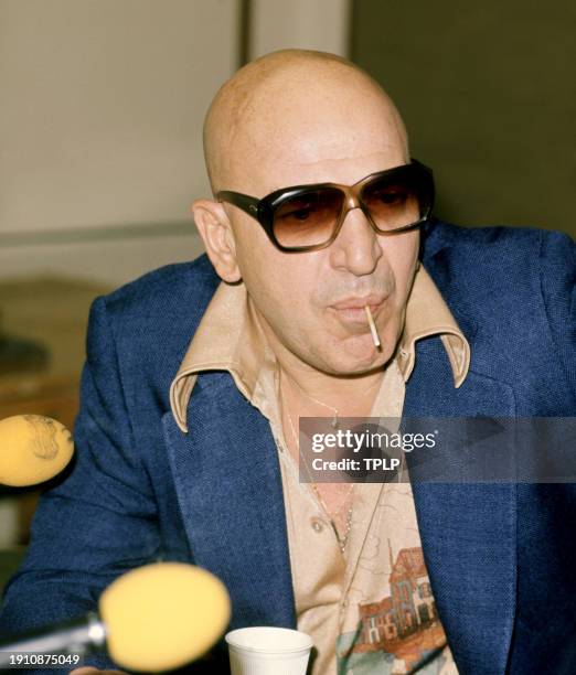 Greek American actor Telly Savalas sucks on a lollipop during a press conference in London, England, November 10, 1975.