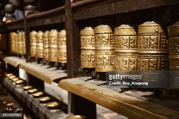 rows of bronze prayer wheel in golden temple in patan, nepal. - tibetan buddhism stock-fotos und bilder
