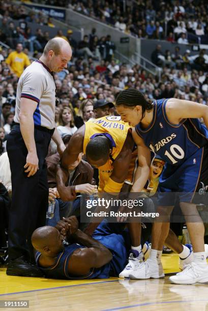 Michael Jordan of the Washington Wizards is helped up from the floor by teammate Tyronn Lue and Kobe Bryant of the Los Angeles Lakers during the game...