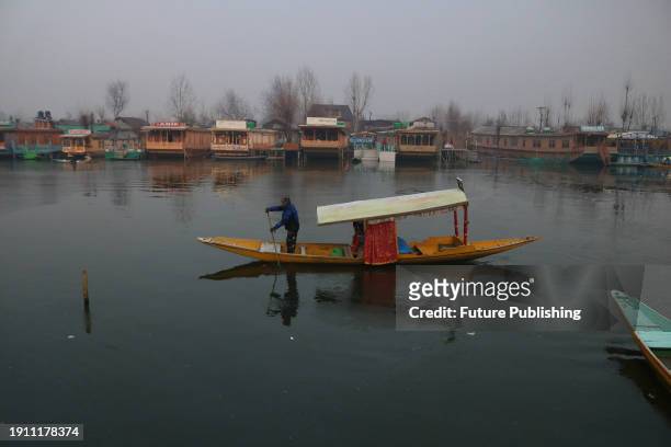 January 08 Srinagar Kashmir, India : A man rows a boat near a frozen portion of Dal Lake on a cold morning in Srinagar. The 40-day harsh winter...