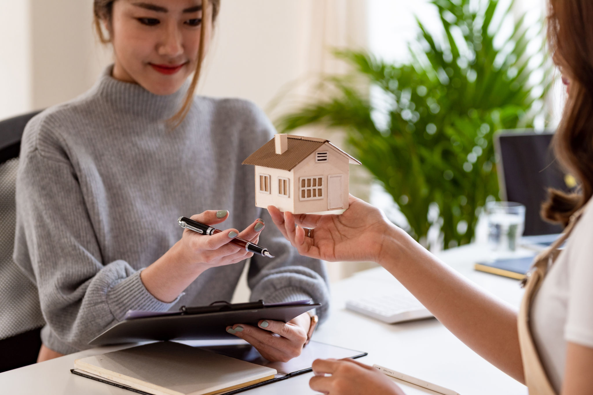 Real estate agent hand over the house key to customers after signing a real estate sales contract, handing over ownership. house and real estate trading idea. Real estate agent hand over the house key to customers after signing a real estate sales contract, handing over ownership. house and real estate trading idea.