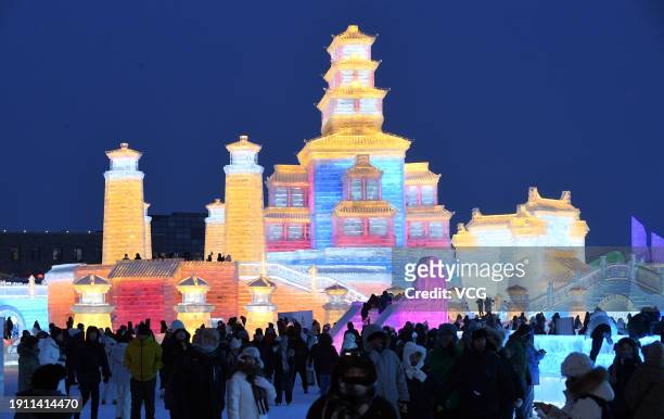 Tourists view ice sculptures illuminated by colored lights at the Harbin Ice and Snow World during the 40th Harbin International Ice and Snow...